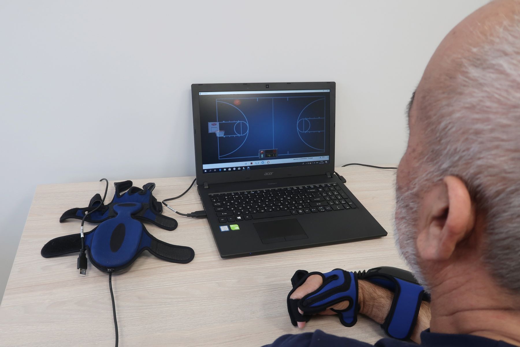 Сжимая и разжимая руку, пациент управляет баскетбольной корзиной и ловит мячи